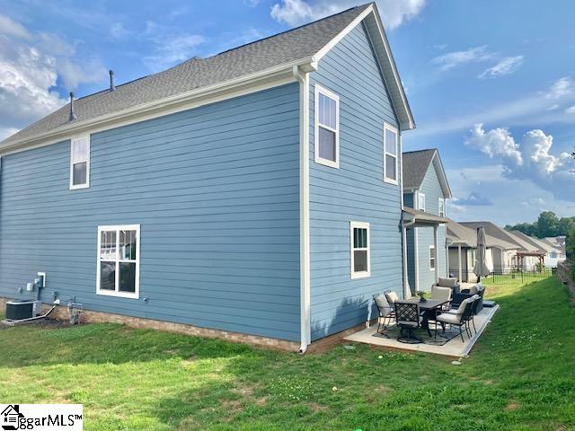 rear view of house featuring a patio, an outdoor hangout area, central AC unit, and a lawn