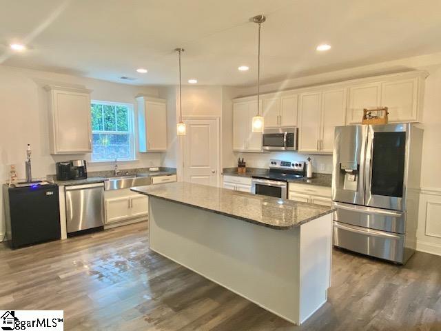 kitchen featuring pendant lighting, dark hardwood / wood-style flooring, a kitchen island, white cabinetry, and appliances with stainless steel finishes