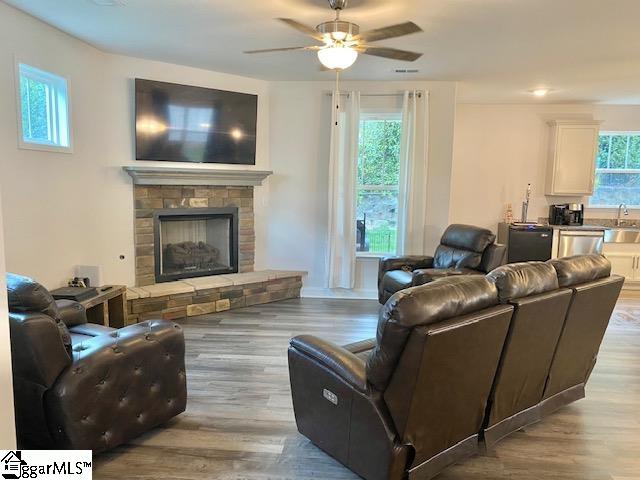 living room with a healthy amount of sunlight, hardwood / wood-style floors, and a stone fireplace