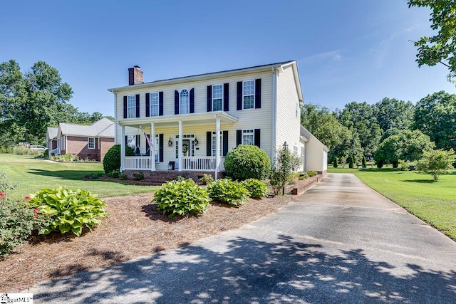 colonial house with a front yard and covered porch