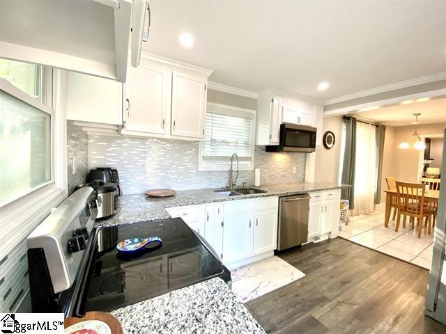 kitchen with tasteful backsplash, stainless steel appliances, light tile flooring, sink, and white cabinets