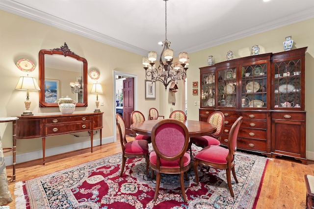 dining area with light wood-type flooring, an inviting chandelier, and ornamental molding