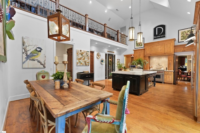 dining area with high vaulted ceiling and light hardwood / wood-style floors