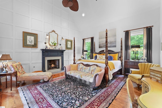 bedroom featuring a brick fireplace, high vaulted ceiling, and hardwood / wood-style flooring