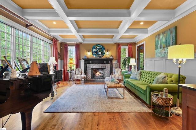 living room featuring hardwood / wood-style flooring, coffered ceiling, crown molding, and a tiled fireplace