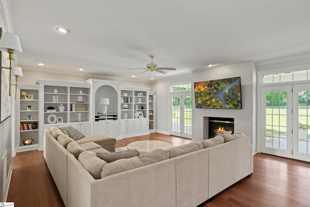 living room with a warm lit fireplace, ceiling fan, recessed lighting, dark wood-style flooring, and crown molding