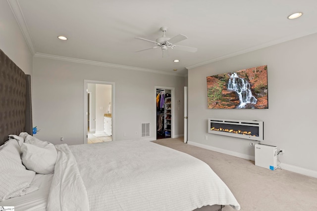 carpeted bedroom with a walk in closet, recessed lighting, visible vents, ornamental molding, and baseboards