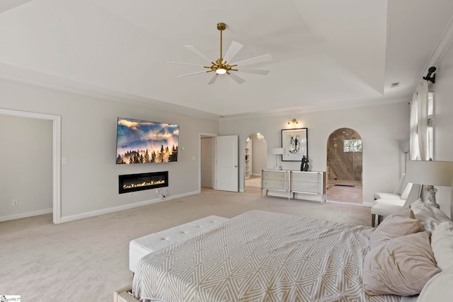 bedroom featuring light carpet, baseboards, arched walkways, and a tray ceiling