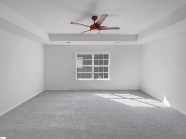 empty room featuring light colored carpet, a raised ceiling, and ceiling fan