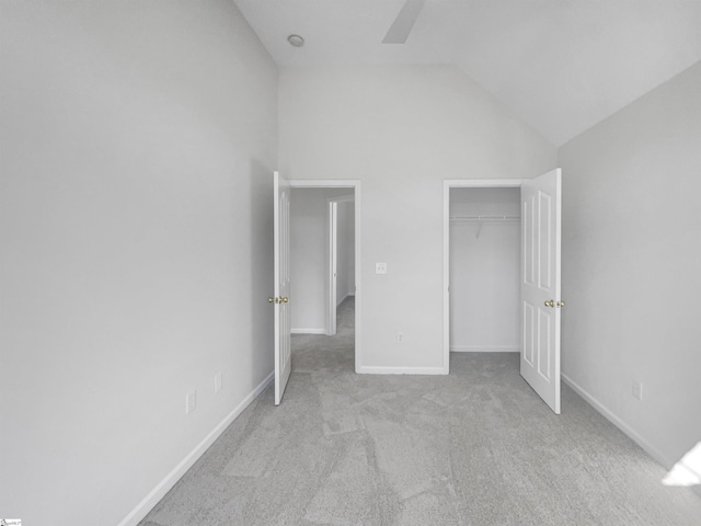 unfurnished bedroom with ceiling fan, a closet, light carpet, and vaulted ceiling