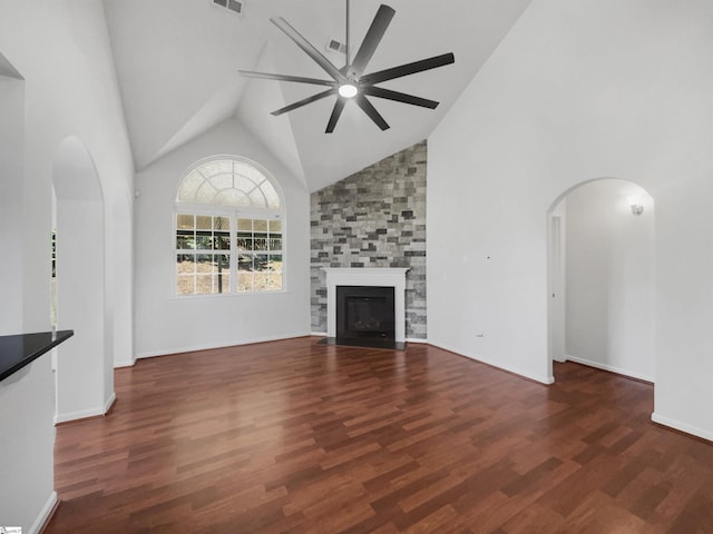 unfurnished living room with ceiling fan, a large fireplace, dark wood-type flooring, and high vaulted ceiling