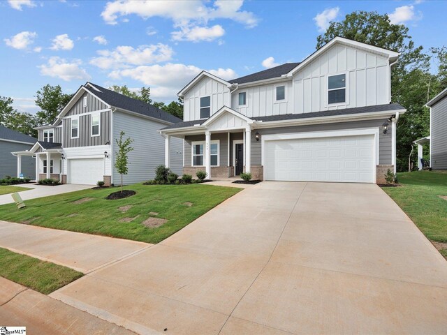 view of front facade with covered porch, a front yard, and a garage