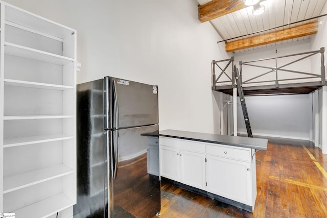 kitchen featuring black refrigerator, white cabinets, dark hardwood / wood-style floors, and beamed ceiling