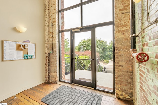 doorway with light wood-type flooring and brick wall