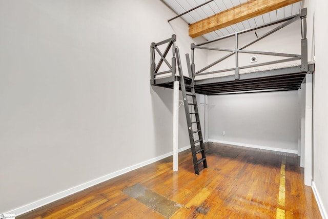 unfurnished bedroom with beam ceiling and hardwood / wood-style floors