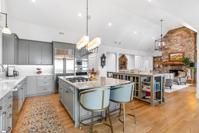 kitchen featuring a center island, light hardwood / wood-style floors, a fireplace, and appliances with stainless steel finishes