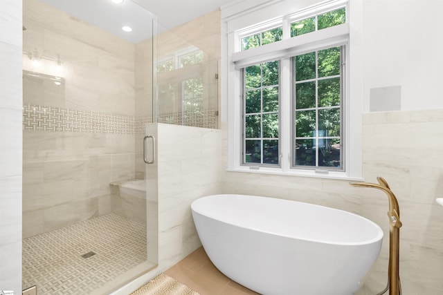 bathroom featuring tile floors, independent shower and bath, and tile walls