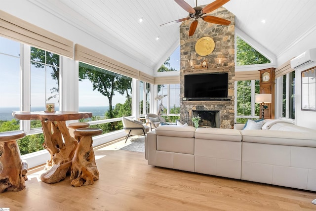 living room with a fireplace, light wood-type flooring, a wall mounted AC, high vaulted ceiling, and ceiling fan