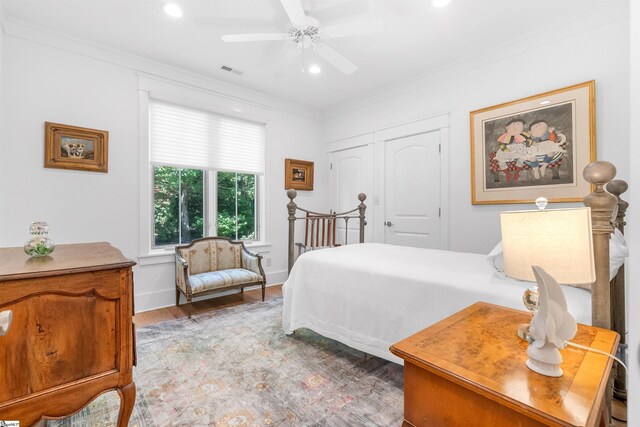 bedroom with hardwood / wood-style floors, a closet, ceiling fan, and crown molding