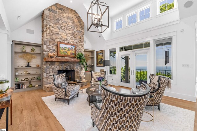 living room with a stone fireplace, high vaulted ceiling, light hardwood / wood-style floors, and a healthy amount of sunlight