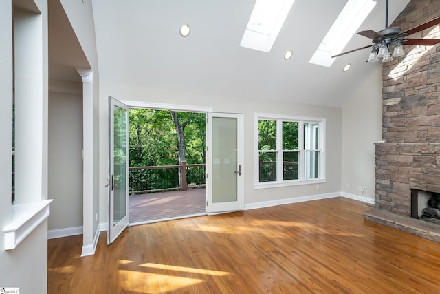 unfurnished living room with hardwood / wood-style floors, a fireplace, a skylight, and ceiling fan