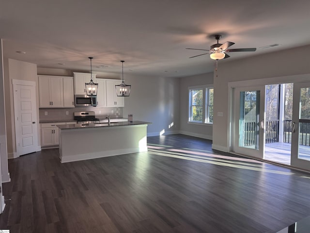 kitchen with pendant lighting, dark wood-type flooring, an island with sink, white cabinetry, and stainless steel appliances