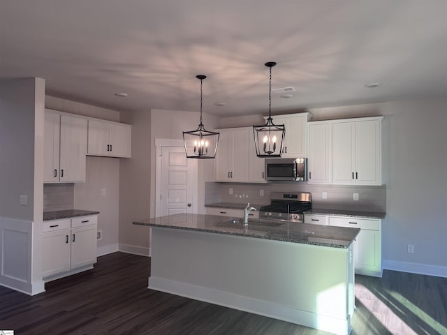 kitchen with white cabinets, appliances with stainless steel finishes, and a center island with sink