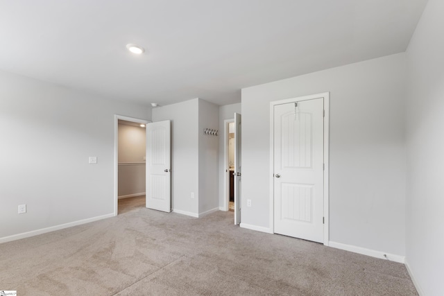 unfurnished bedroom featuring light colored carpet and a closet