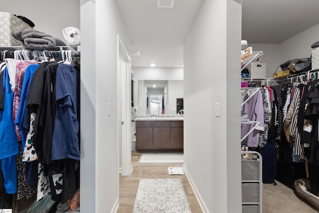 walk in closet with sink and light hardwood / wood-style floors