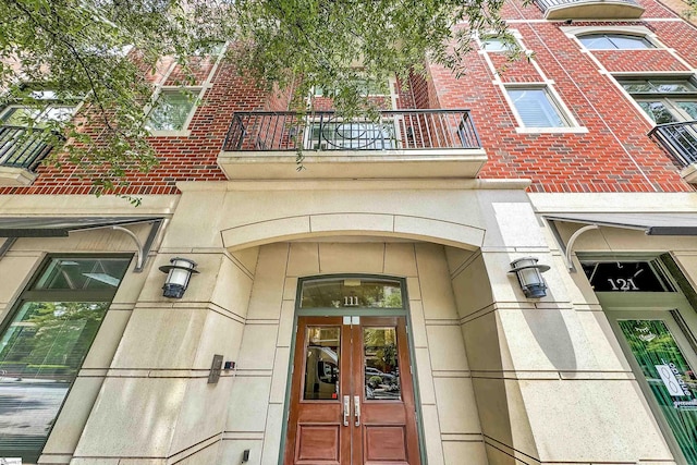 view of exterior entry with a balcony and french doors