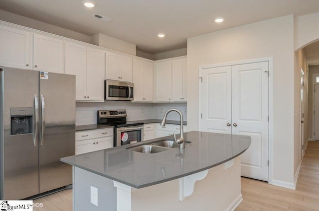 kitchen with white cabinetry, sink, stainless steel appliances, light hardwood / wood-style floors, and a kitchen island with sink