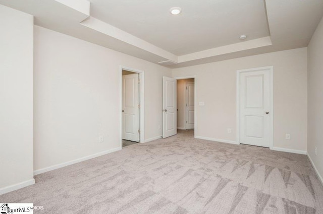 unfurnished bedroom with a raised ceiling and light carpet