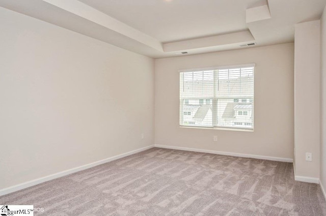 carpeted empty room featuring a tray ceiling