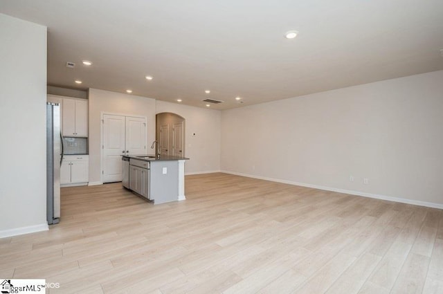 kitchen with white cabinets, sink, light hardwood / wood-style flooring, an island with sink, and appliances with stainless steel finishes