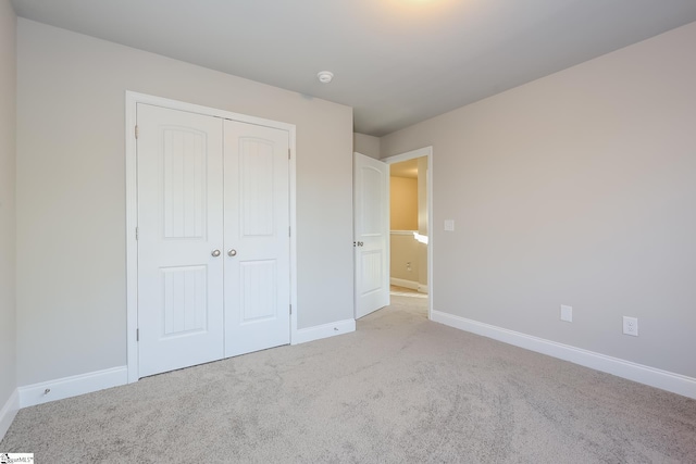 unfurnished bedroom with light carpet and a closet