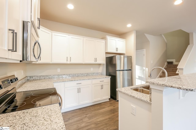 kitchen with white cabinetry, sink, light hardwood / wood-style flooring, and appliances with stainless steel finishes