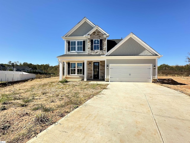 view of front of house with a garage, stone siding, fence, and driveway