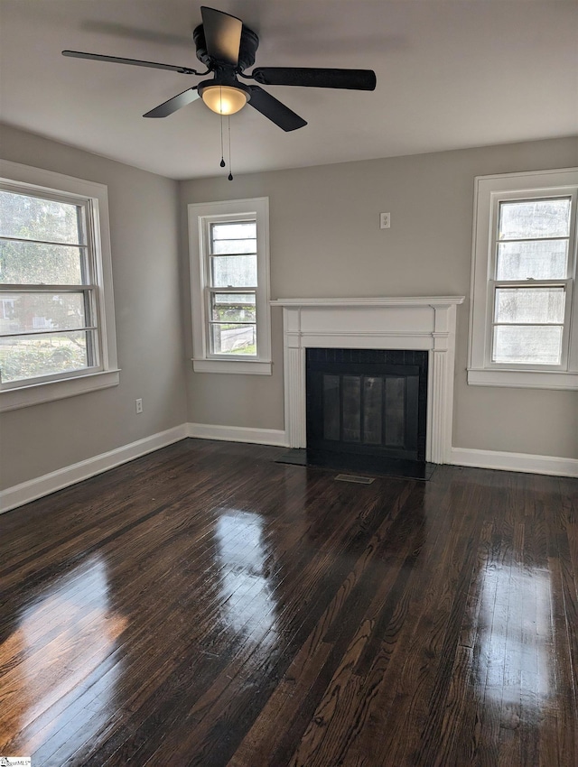 unfurnished living room featuring dark wood-type flooring and ceiling fan