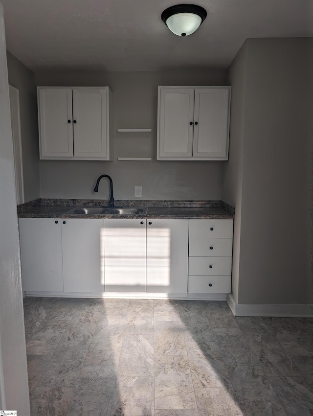 kitchen featuring white cabinetry, sink, and dark stone counters