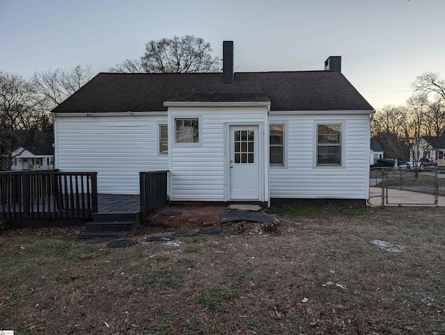 back house at dusk with a wooden deck