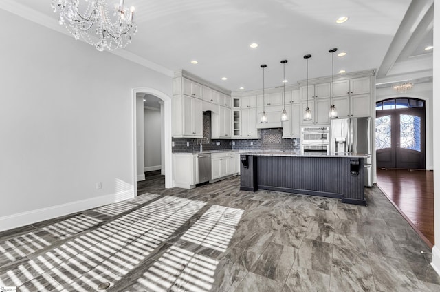 kitchen with an island with sink, a breakfast bar area, stainless steel appliances, tasteful backsplash, and decorative light fixtures