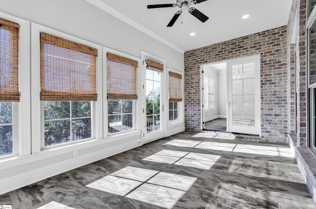 unfurnished sunroom with ceiling fan with notable chandelier