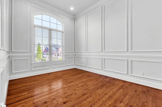 empty room with hardwood / wood-style flooring and crown molding