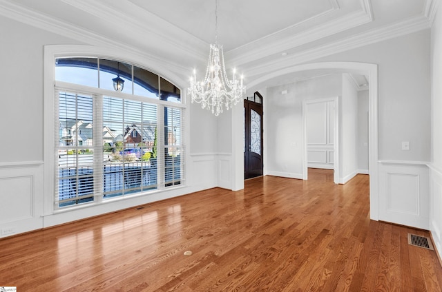 unfurnished dining area with a notable chandelier, ornamental molding, and hardwood / wood-style flooring