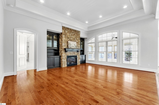 unfurnished living room featuring ceiling fan, light wood-type flooring, crown molding, and a fireplace