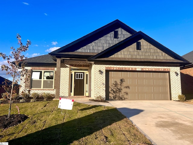 craftsman-style home featuring driveway, brick siding, an attached garage, and a front yard