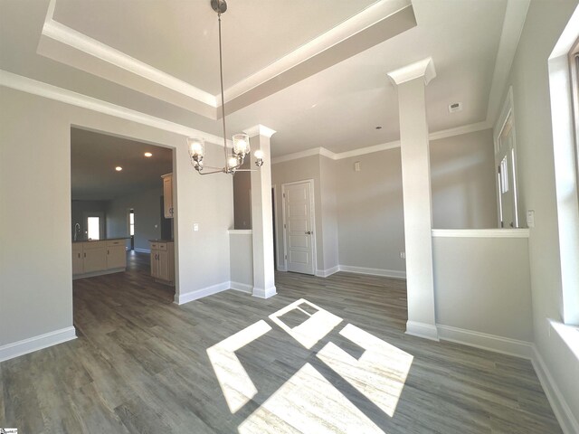 unfurnished dining area with dark wood-style floors, a tray ceiling, crown molding, and baseboards