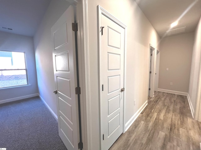 hall with wood finished floors, visible vents, and baseboards