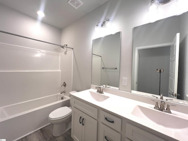 bathroom featuring toilet, visible vents, a sink, and wood finished floors