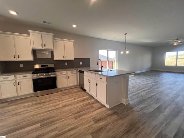 kitchen with visible vents, white cabinets, decorative backsplash, appliances with stainless steel finishes, and a peninsula